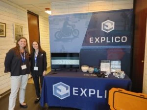 Two Explico representatives stand at a sponsored table at 2024 Marine Law Symposium.