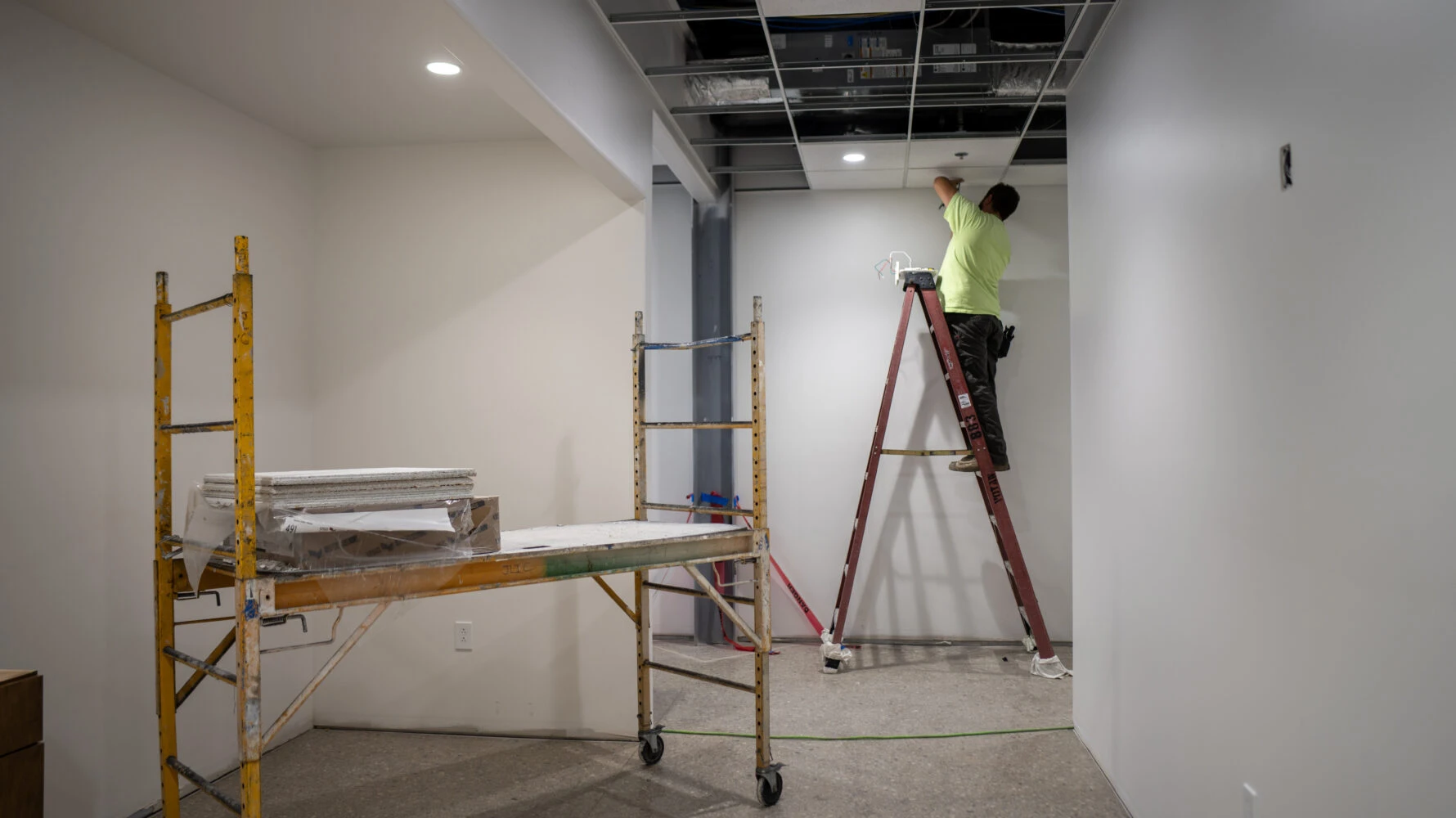 Man standing on ladder working on interior construction of building