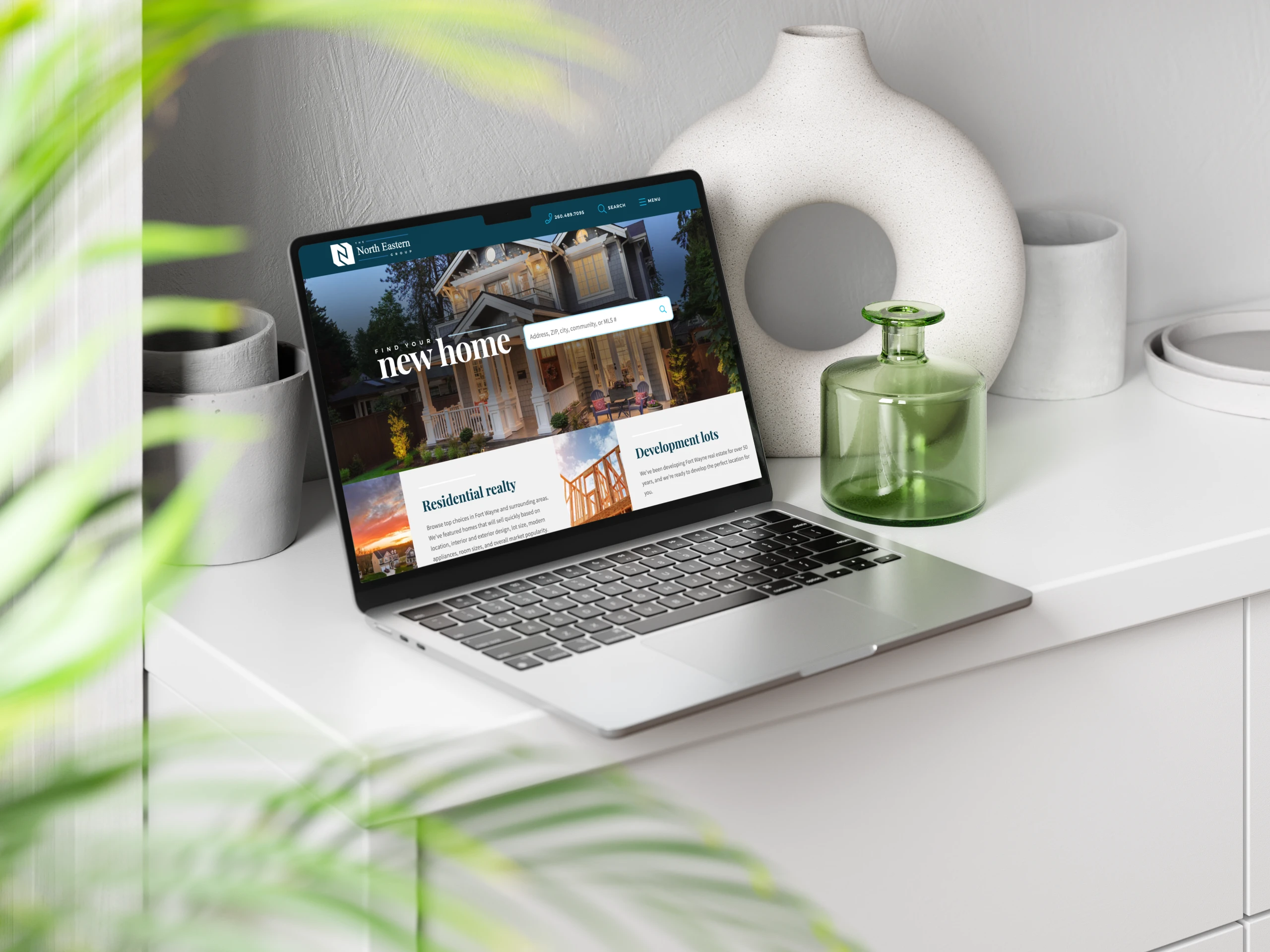 A mockup of a laptop showing the Northeastern Group Realty website