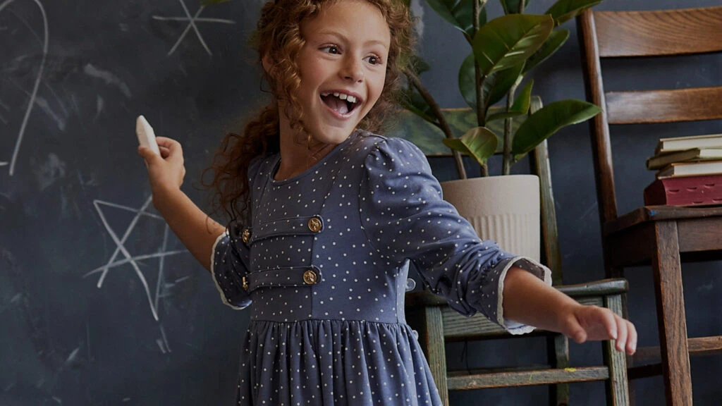 Young girl at chalkboard wearing Finding Foxtale clothes