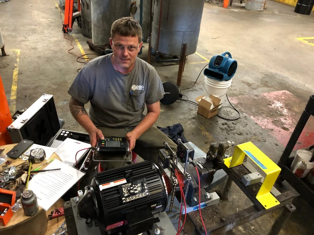 Millwright using intrinsically safe laser alignment equipment on industrial machinery