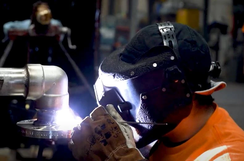 Technician performing precision pipe welding on-site at Peña Mechanical facility