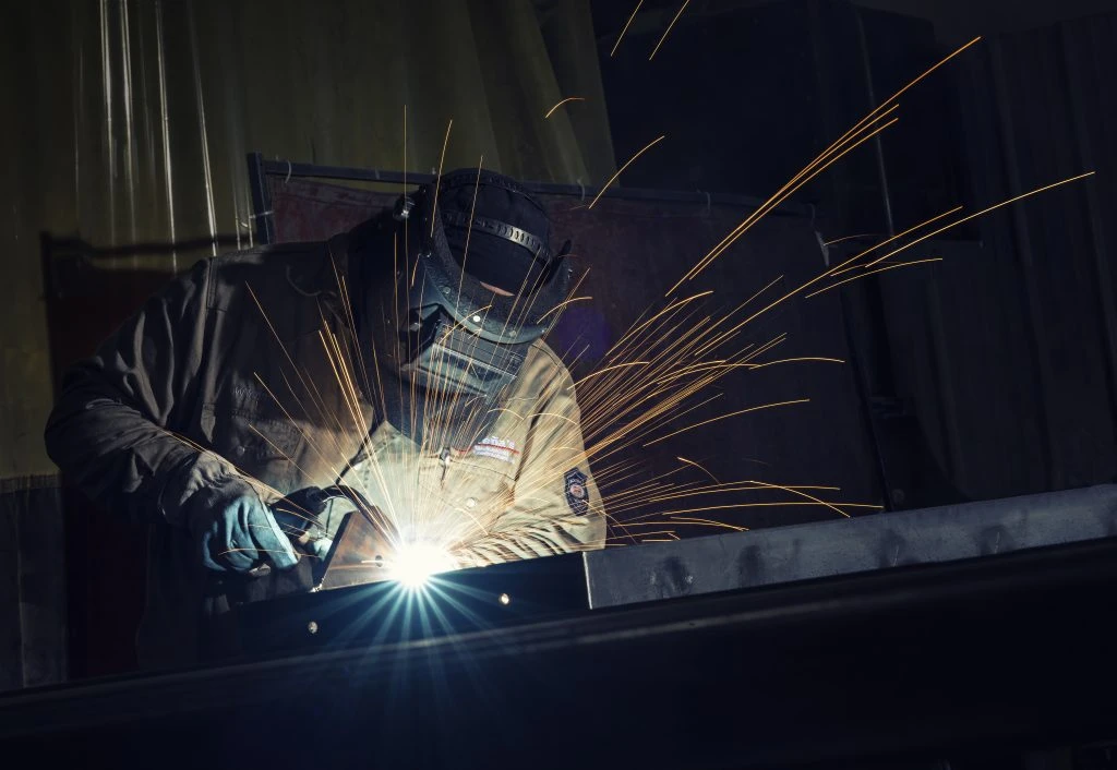 Professional welder performing MIG welding, ARC welding, TIG welding on a custom steel frame inside industrial workshop-ASME Certified