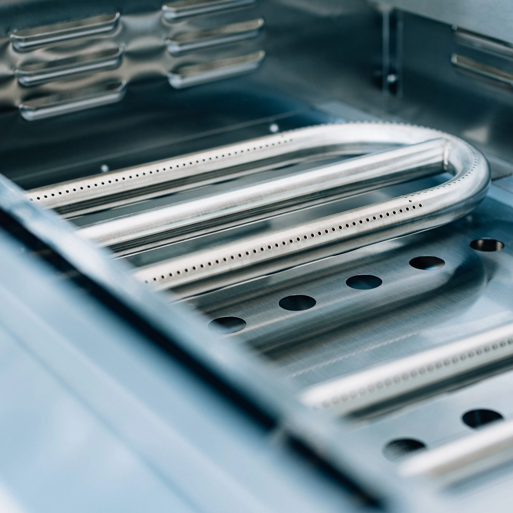 Interior view of the Summerset 30-inch Griddle Pro built-in gas griddle, showing the stainless steel U-tube burner and firebox drainage ports