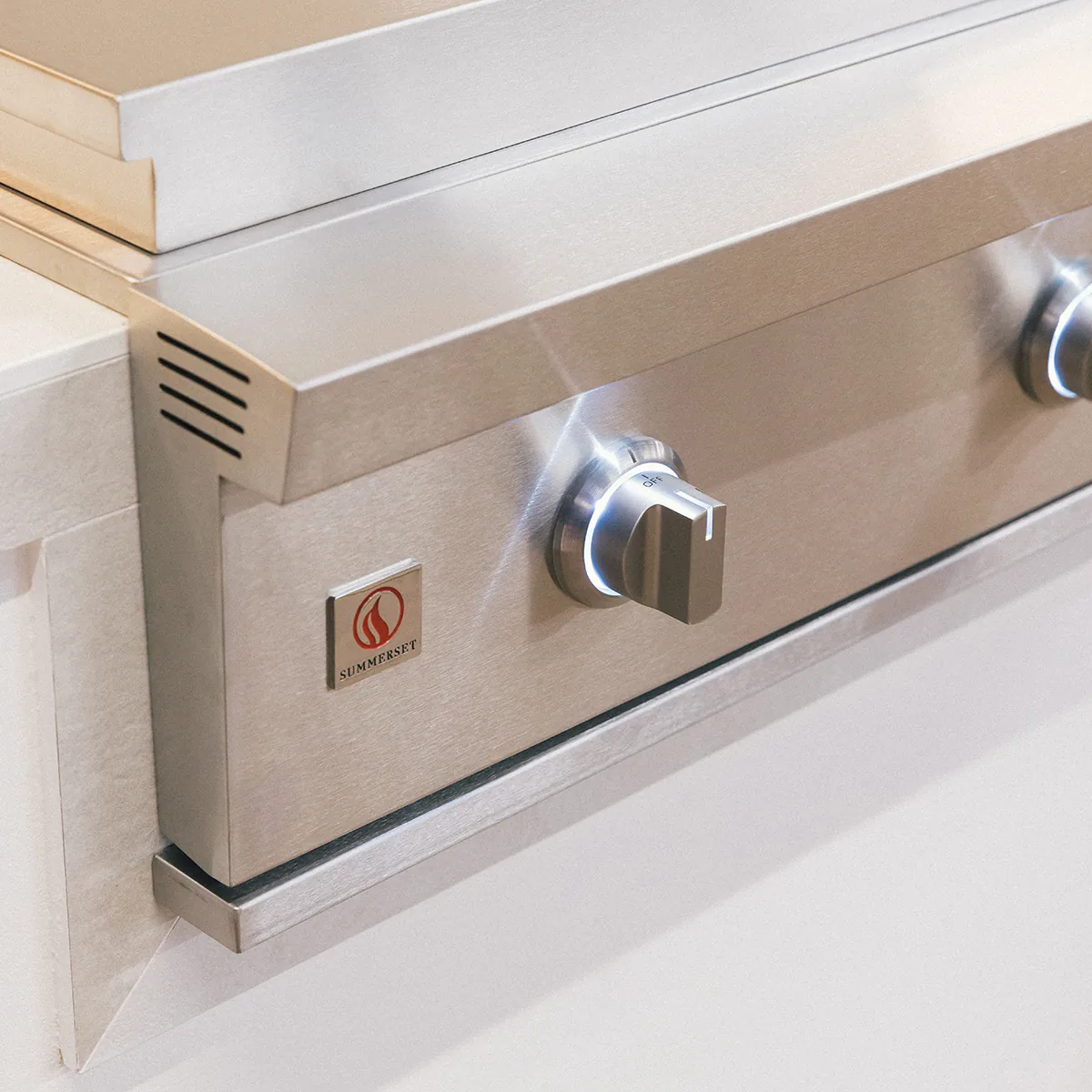 Control panel of the Summerset GRID30 30-inch gas griddle showing the Summerset badge, illuminated knobs and side vent louvers