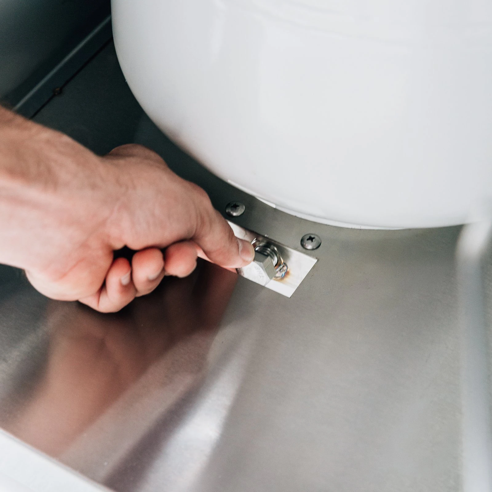 Hand securing the propane tank safety strap inside a Summerset grill cart's storage compartment