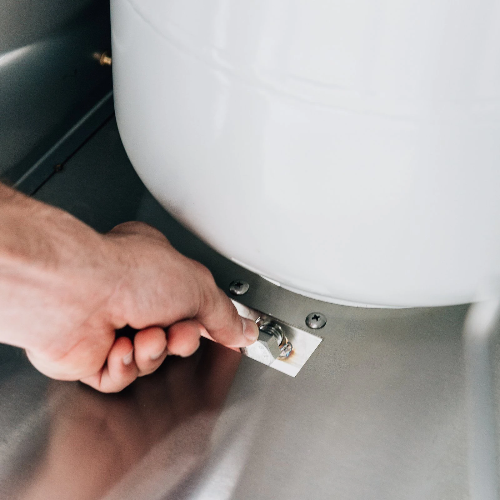 Hand securing the propane tank safety strap inside a Summerset grill cart's storage compartment