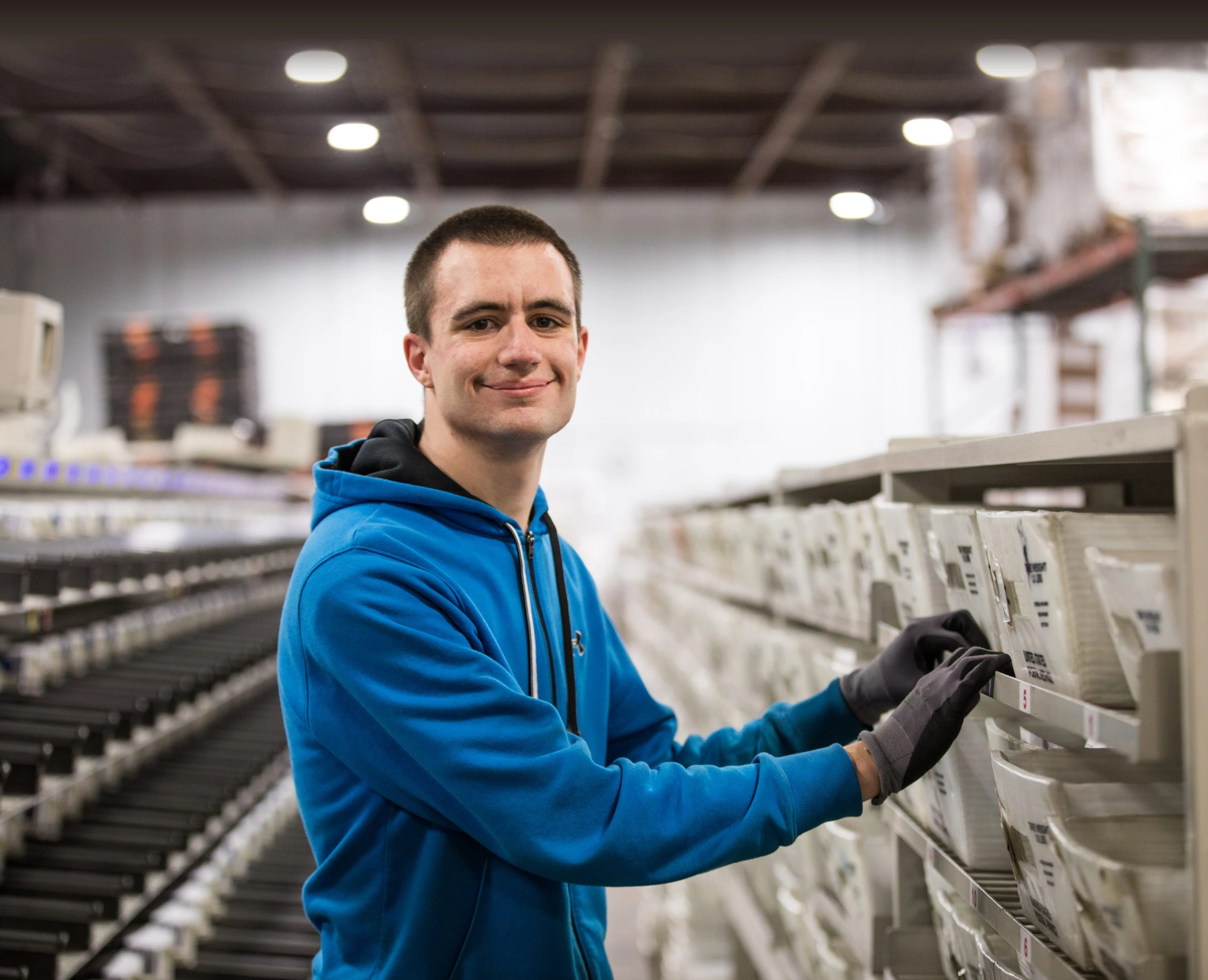 Person standing in front of postage bins smiling